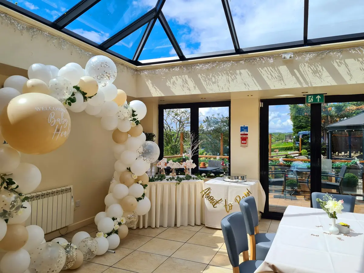 Party setup with balloon arch and dressed tables in a sunlit room