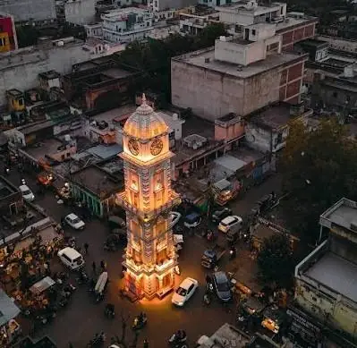 Sikar's clock tower lit up at dusk above the city's streets