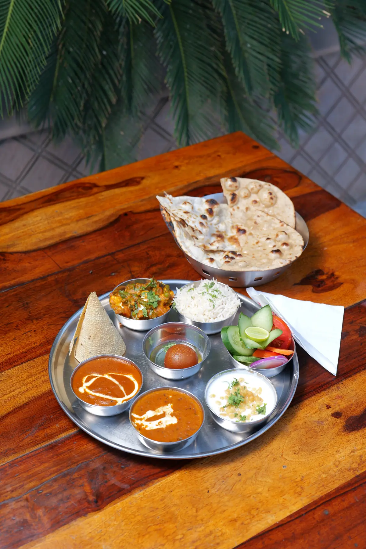 Indian thali with curries, rice, salad, gulab jamun and butter naan