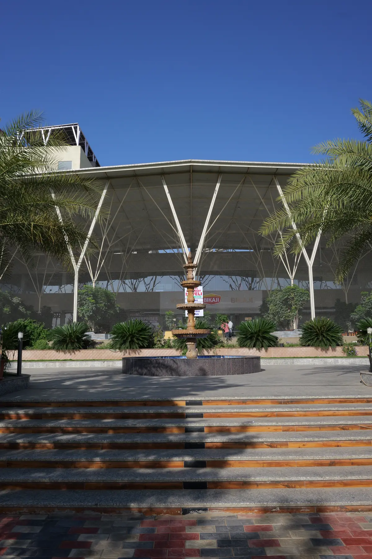 Fountain and palms in front of the tree-like steel canopy