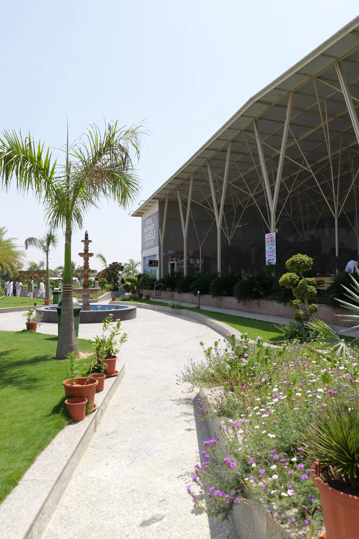 Palm-lined garden walkway with a fountain beside the main building